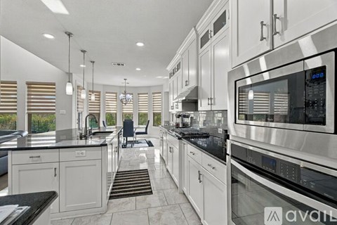 A modern kitchen with white cabinets and stainless steel appliances.