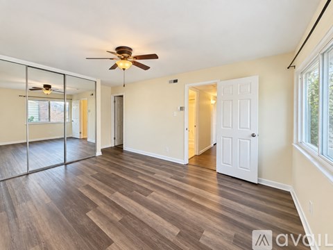 A spacious room with wood flooring and a ceiling fan.