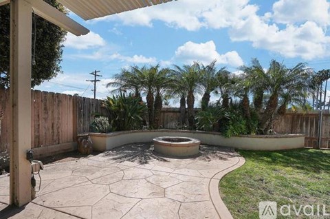 A backyard with a circular patio and a pool surrounded by a wooden fence.