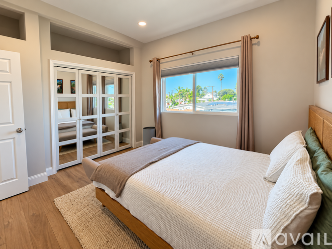 A bedroom with a large bed and a view of the street through the window.