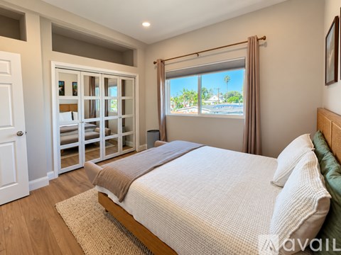 A bedroom with a large bed and a view of the street through the window.