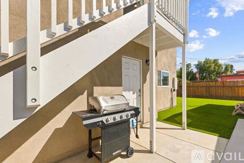 A BBQ grill is on a patio next to a white door.