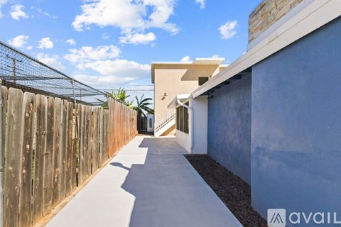 A modern house with a wooden fence and a concrete pathway leading to the entrance.