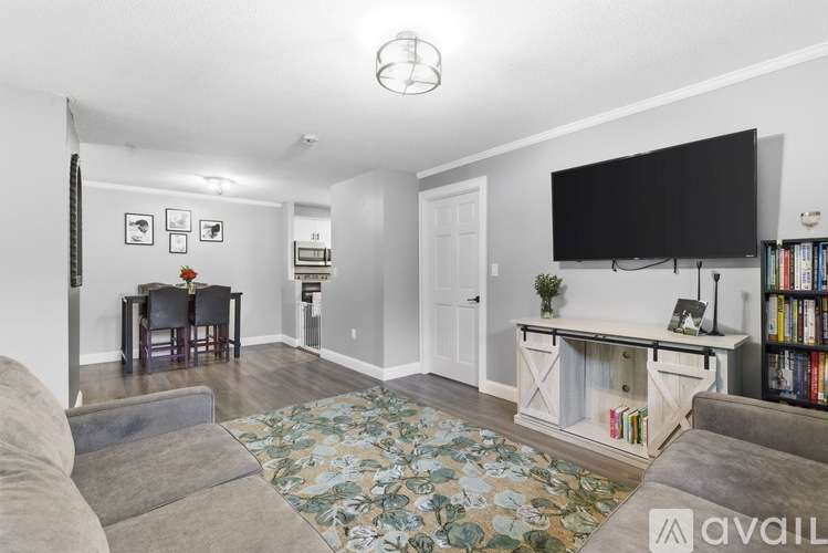 A living room with a grey couch, a television, and a rug with a floral pattern.