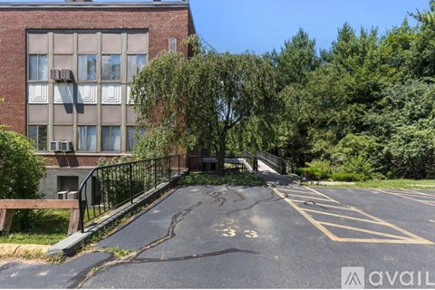 A parking lot in front of a brick building with trees on the side.
