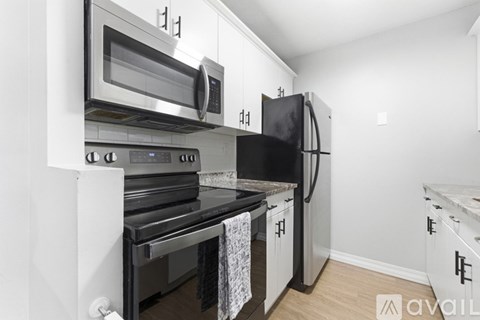 A kitchen with a black fridge and stove top oven.