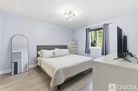 A bedroom with a large bed and a television on a stand.