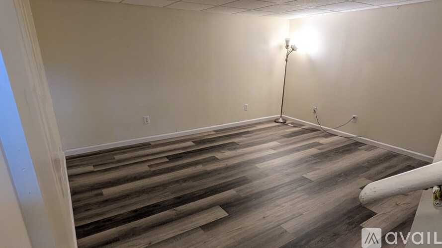 A room with wooden flooring and a white wall.