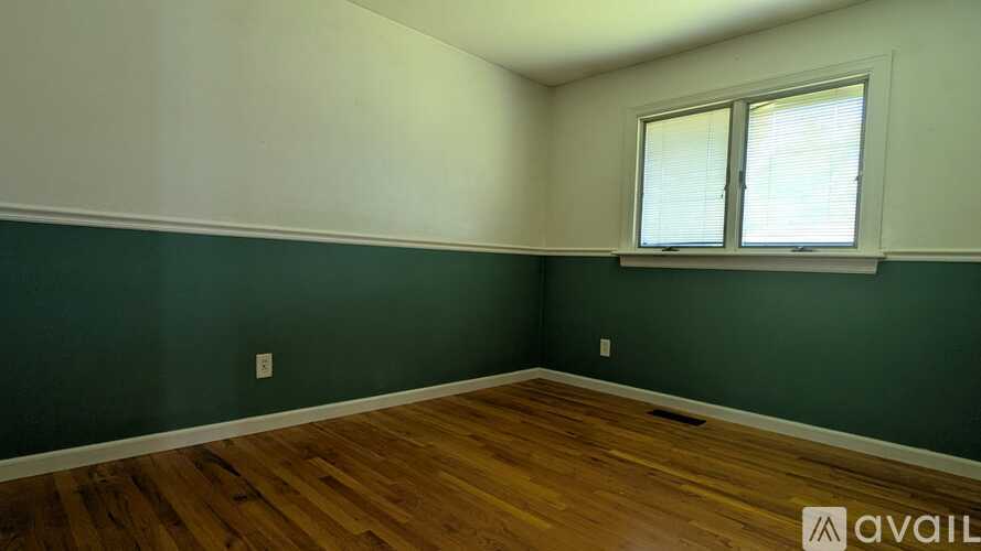 A room with wooden flooring and a window with blinds.
