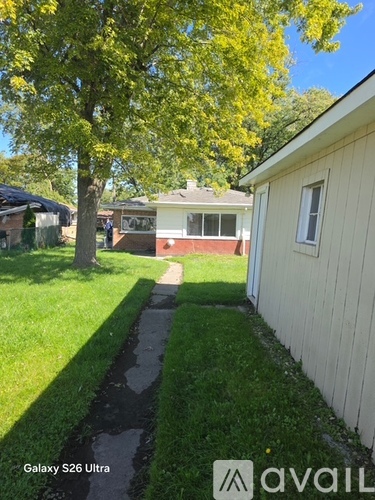 A tree with yellow leaves is in front of a house.