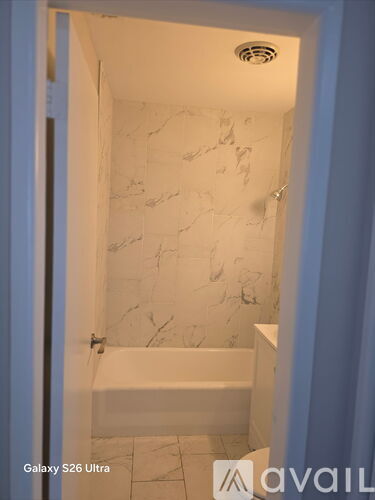 A bathroom with a marble wall and a white bathtub.