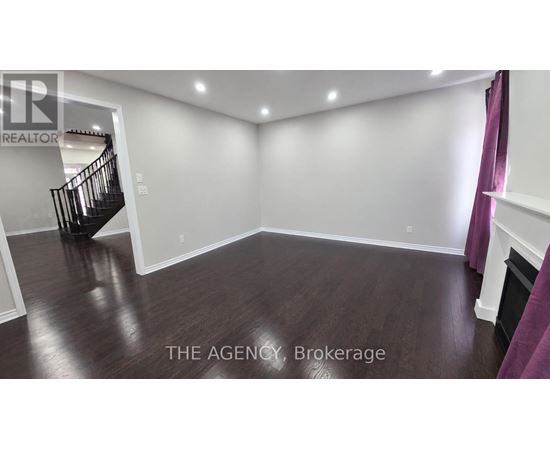 A spacious room with a staircase and wooden flooring.