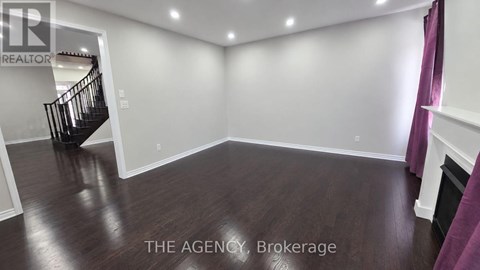 A spacious room with a staircase and wooden flooring.