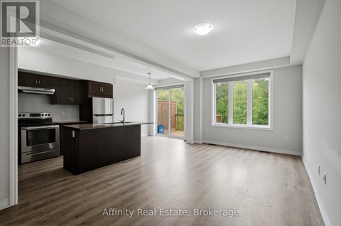 A spacious kitchen with dark wood floors and white walls.