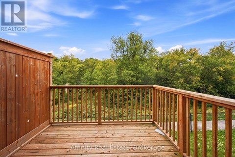 A wooden deck with a railing and a view of trees in the distance.