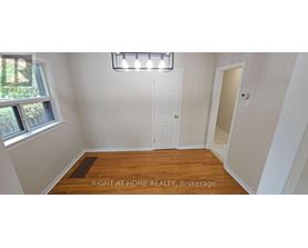 A room with a white door and a window with a view of trees and a sign that says "REALTOR".