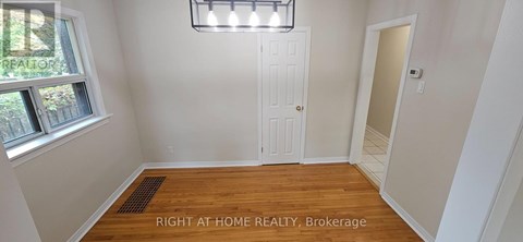 A room with a white door and a window with a view of trees and a sign that says "REALTOR".