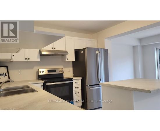 A kitchen with a refrigerator, oven, and sink.