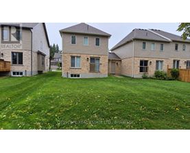 A real estate company is advertising a property with a large grassy area in front of a two-story house.