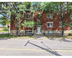 A red brick building with a black iron fence and a stop sign in front.