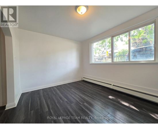A room with a large window and wooden flooring.