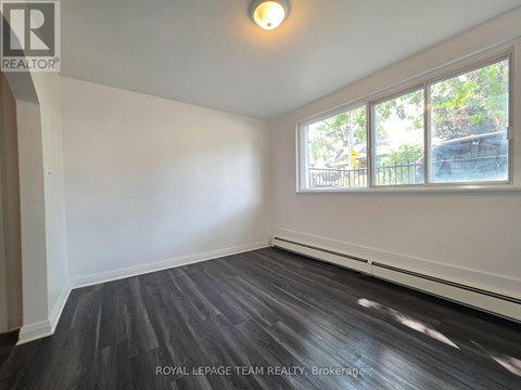A room with a large window and wooden flooring.