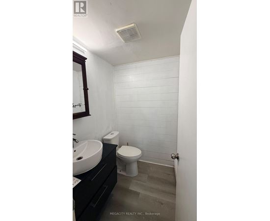 A white tiled bathroom with a toilet, sink, and mirror.