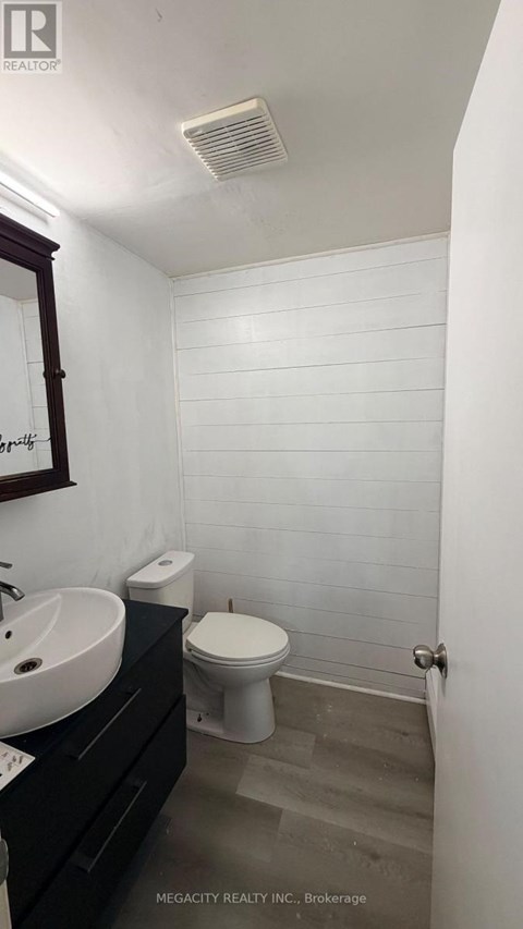 A white tiled bathroom with a toilet, sink, and mirror.