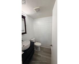 A white tiled bathroom with a toilet, sink, and mirror.
