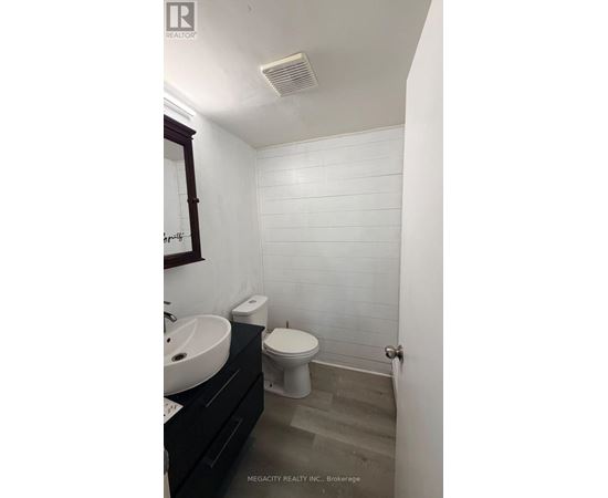 A white tiled bathroom with a toilet, sink, and mirror.