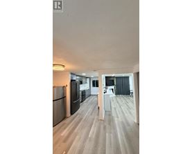 A kitchen with a refrigerator, oven, and sink.