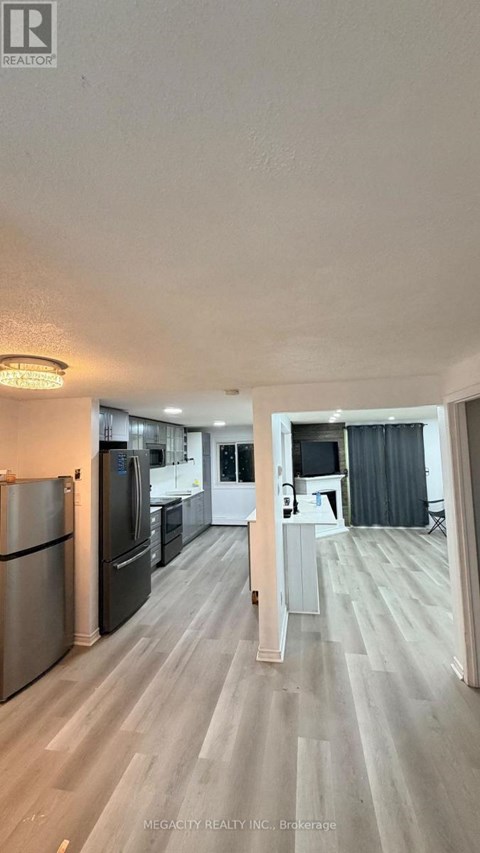 A kitchen with a refrigerator, oven, and sink.