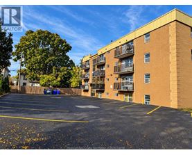 A parking lot in front of a brick apartment building.