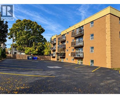 A parking lot in front of a brick apartment building.