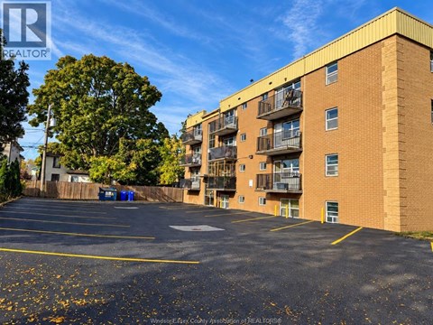 A parking lot in front of a brick apartment building.