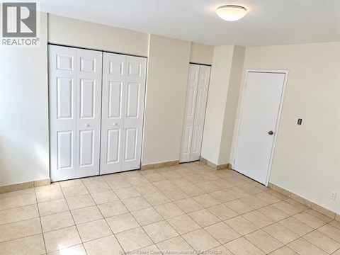 A room with white doors and tiled flooring.