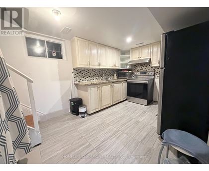 A kitchen with white cabinets and a black refrigerator.