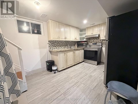 A kitchen with white cabinets and a black refrigerator.