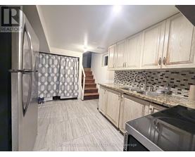 A kitchen with a refrigerator, sink, and cabinets.