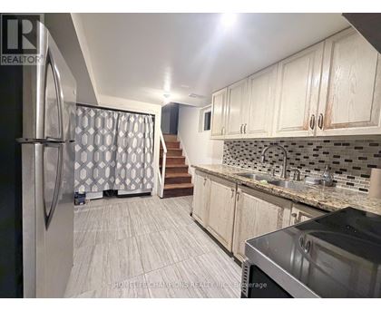 A kitchen with a refrigerator, sink, and cabinets.