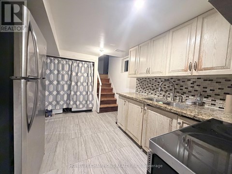 A kitchen with a refrigerator, sink, and cabinets.
