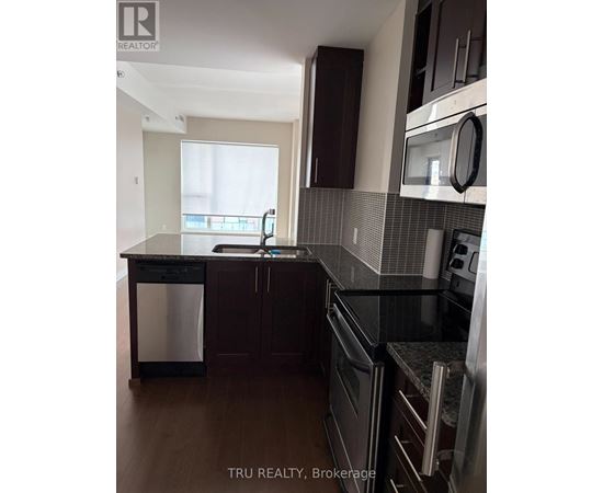 A kitchen with dark wood cabinets and black appliances.