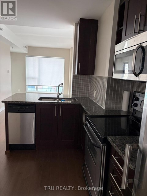 A kitchen with dark wood cabinets and black appliances.