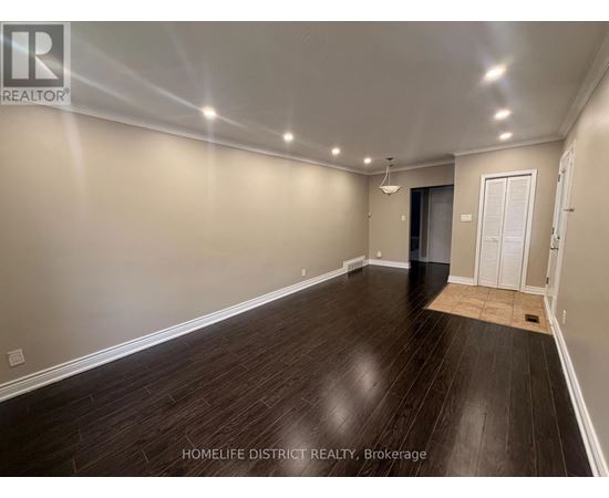 A spacious room with wooden flooring and white walls.