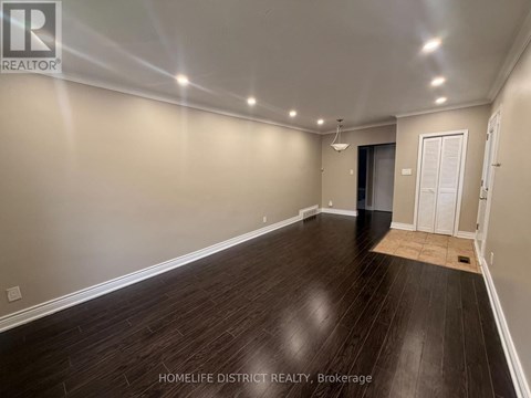 A spacious room with wooden flooring and white walls.