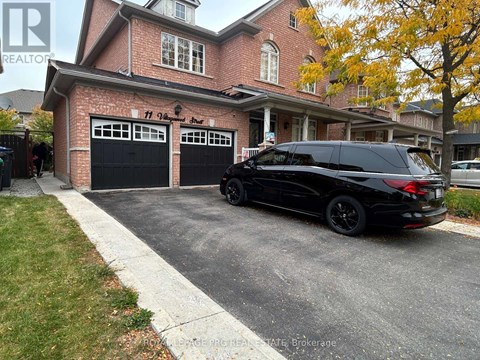 A black SUV is parked in front of a brick house with a garage.