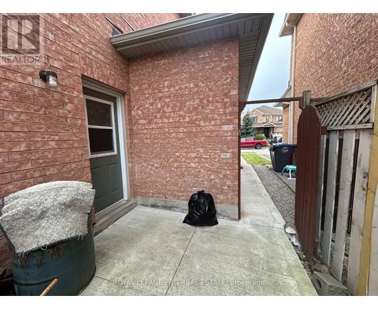 A black bag sits on a concrete walkway outside a brick building.