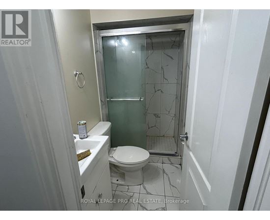 A white toilet in a small bathroom with a glass shower door.