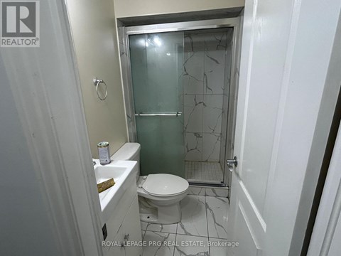 A white toilet in a small bathroom with a glass shower door.