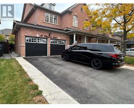 A black SUV is parked in front of a brick house with a garage.
